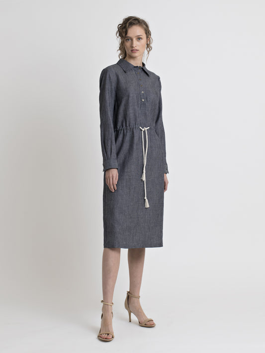 Full view of a female model wearing a knee length long sleeve straight cut denim shirt dress with drawstring inserted belt and high heel nude sandals. From the RÉZO women's collection.