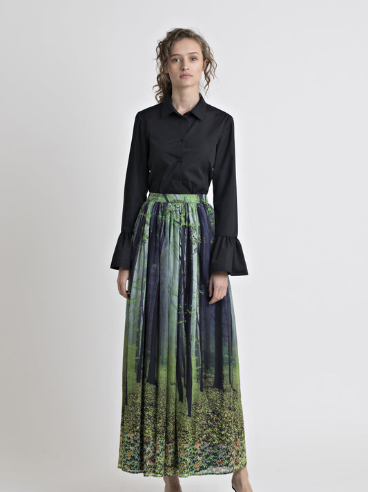 Full front view of a female model wearing a black cotton flared cuff dress shirt, and a long cotton forest print gathered skirt, from the RÉZO women's collection.