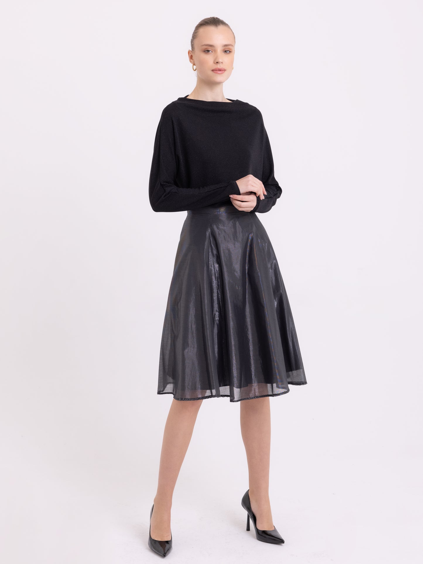 Bat silhouette black lurex top, with cowl neck and long sleeves. Paired with a knee length shiny flared skirt.