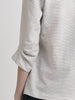 Back left torso view of a female model wearing an off white terry blouse with coffee color circle pattern and a dart  detail on the 3/4 sleeve edge. From the RÉZO women's collection.