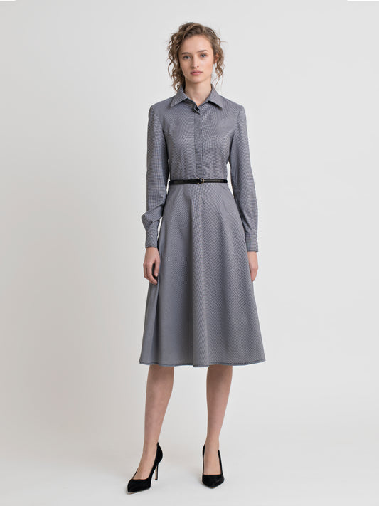 Front view of a female model, wearing high heel black shoes, and a semi fitted black and white check shirt dress, with covered placket and a patent leather black narrow belt. From the RÉZO women's collection.